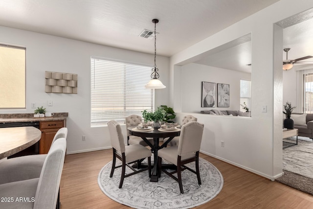 dining room featuring baseboards, visible vents, ceiling fan, and wood finished floors