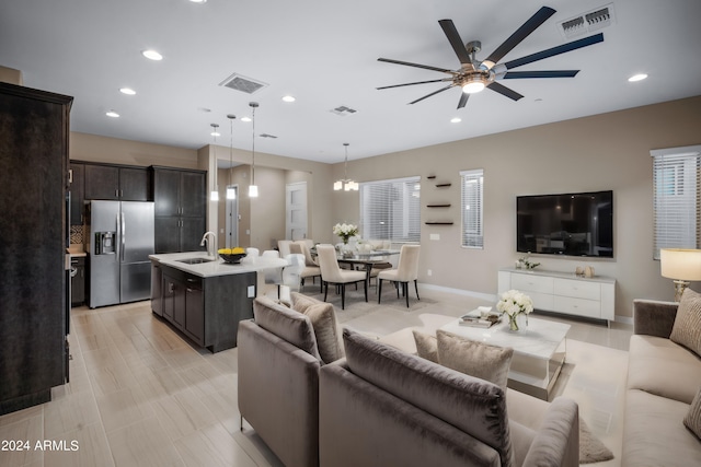 living room featuring ceiling fan with notable chandelier and sink