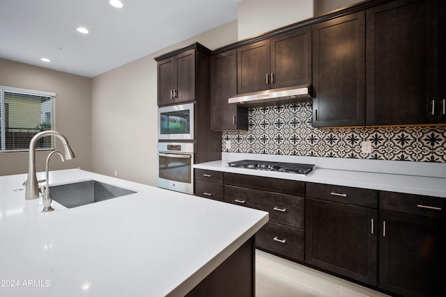 kitchen featuring appliances with stainless steel finishes, backsplash, dark brown cabinets, and sink