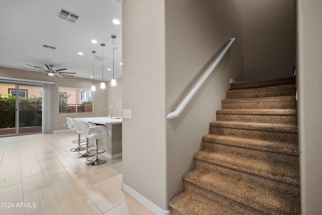 stairs with sink, ceiling fan, and tile patterned floors