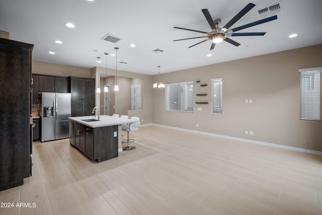 kitchen with ceiling fan with notable chandelier, decorative light fixtures, a center island with sink, sink, and stainless steel fridge with ice dispenser