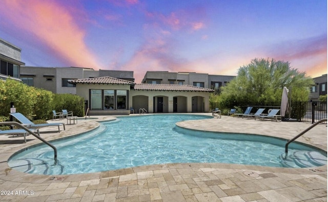 pool at dusk with a patio area