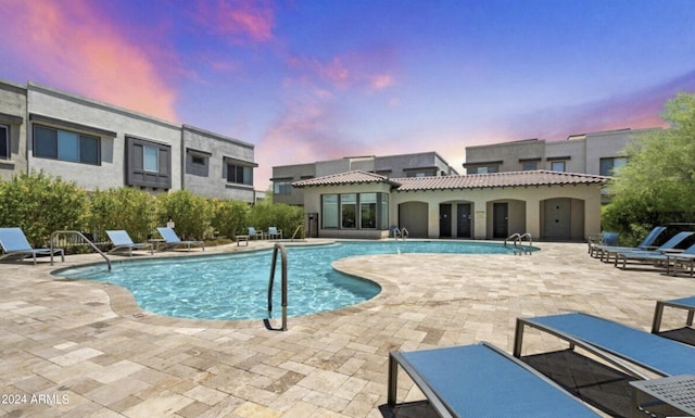 pool at dusk featuring a patio area