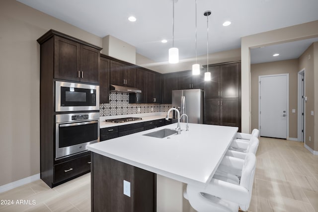 kitchen featuring dark brown cabinetry, a kitchen island with sink, appliances with stainless steel finishes, and sink