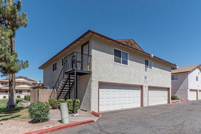 860 E Brown Rd Unit 25, Mesa, AZ 85203 - view of home's exterior featuring an attached garage, stucco siding, stairs, and driveway