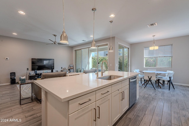 kitchen featuring white cabinets, a center island with sink, stainless steel dishwasher, light hardwood / wood-style floors, and sink