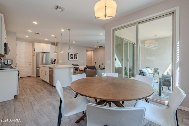 dining area with light hardwood / wood-style flooring, a wealth of natural light, sink, and ceiling fan