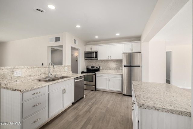 1628 E Sunland Ave, Phoenix, AZ 85040 - kitchen with stainless steel appliances, a sink, a kitchen island with sink, light wood-type flooring, and recessed lighting