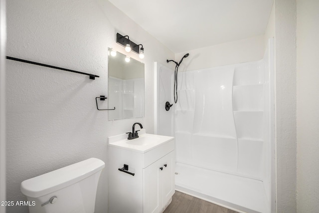 1628 E Sunland Ave, Phoenix, AZ 85040 - bathroom with a shower, toilet, vanity, wood finished floors, and a textured wall