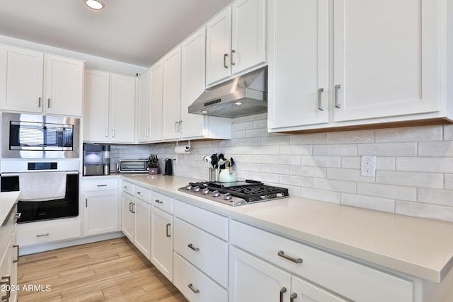 kitchen with backsplash, appliances with stainless steel finishes, light wood-style floors, white cabinetry, and under cabinet range hood