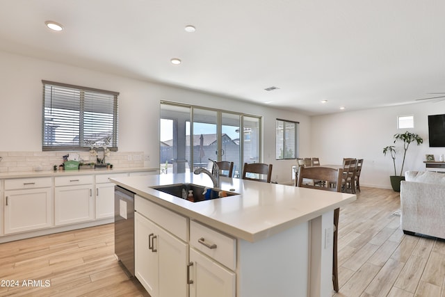 kitchen featuring light countertops, a sink, light wood-style flooring, and stainless steel dishwasher