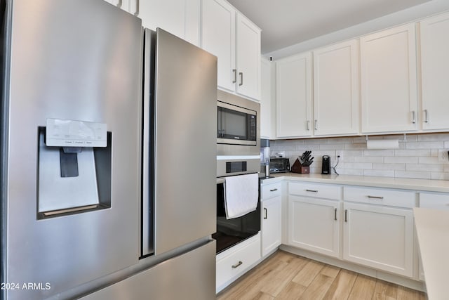 kitchen with light countertops, appliances with stainless steel finishes, white cabinets, and decorative backsplash