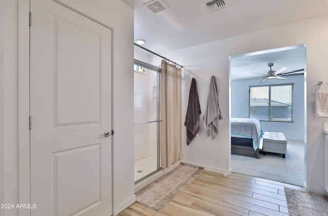 full bath with a stall shower, baseboards, visible vents, and wood finished floors