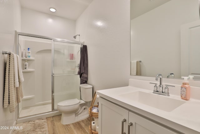 bathroom featuring toilet, a shower stall, wood finished floors, and vanity