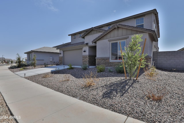 craftsman-style home with stucco siding, board and batten siding, a garage, stone siding, and driveway