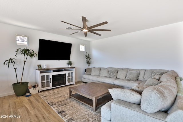 living room with a fireplace, wood finished floors, a ceiling fan, and baseboards