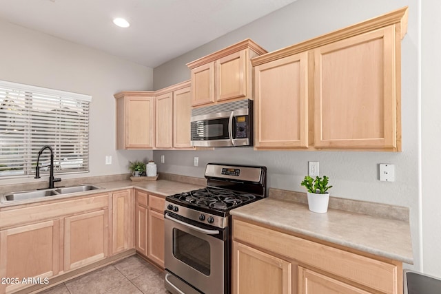 kitchen featuring stainless steel appliances, light brown cabinetry, a sink, and light countertops