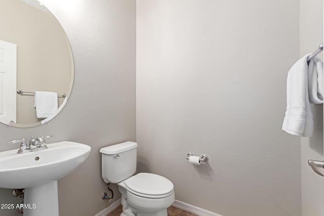 bathroom with baseboards, a sink, and toilet