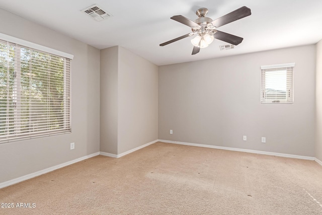 spare room with carpet floors, visible vents, baseboards, and a ceiling fan