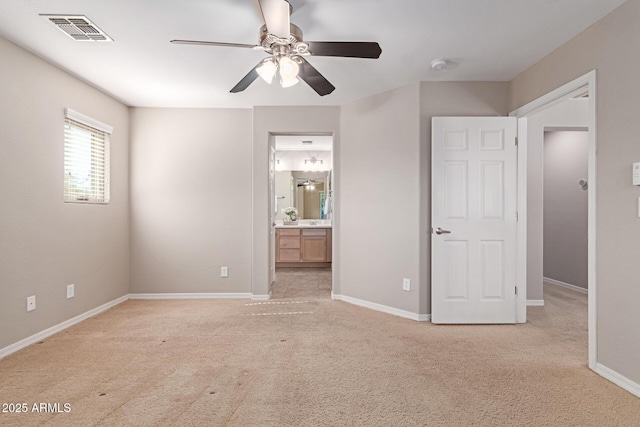 unfurnished bedroom with baseboards, visible vents, ensuite bathroom, and light colored carpet