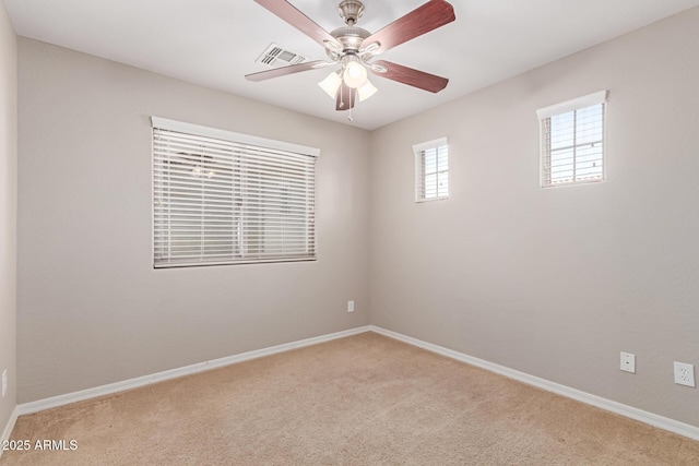 spare room featuring light carpet, ceiling fan, visible vents, and baseboards