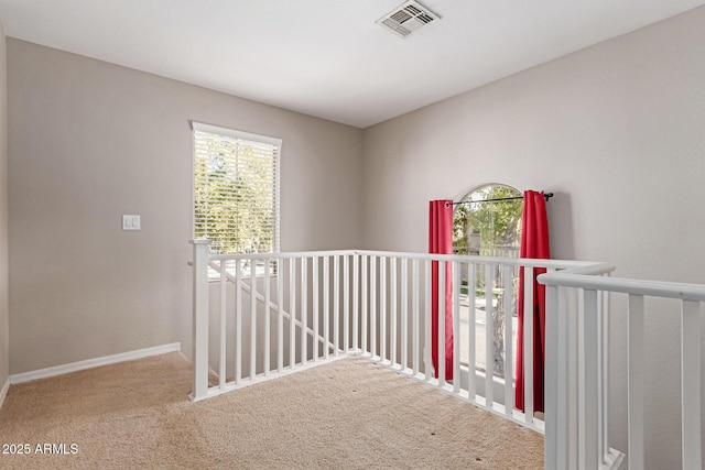 hall with carpet, visible vents, baseboards, and an upstairs landing