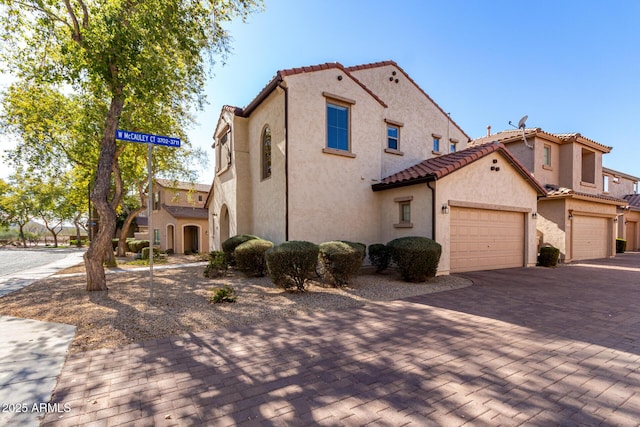 view of front of home with a tile roof, decorative driveway, and stucco siding