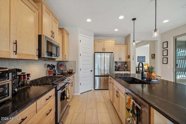 kitchen featuring sink, backsplash, pendant lighting, appliances with stainless steel finishes, and light brown cabinetry