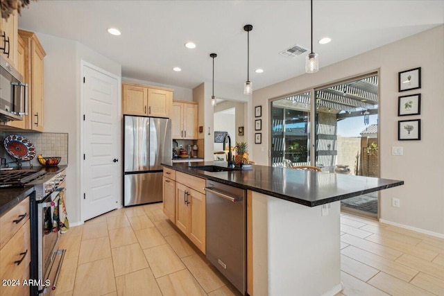 kitchen with sink, appliances with stainless steel finishes, a kitchen breakfast bar, a kitchen island with sink, and pendant lighting