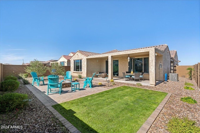 rear view of property with ceiling fan, a patio, and a yard