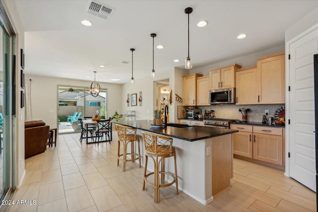 kitchen featuring sink, backsplash, light brown cabinets, appliances with stainless steel finishes, and decorative light fixtures