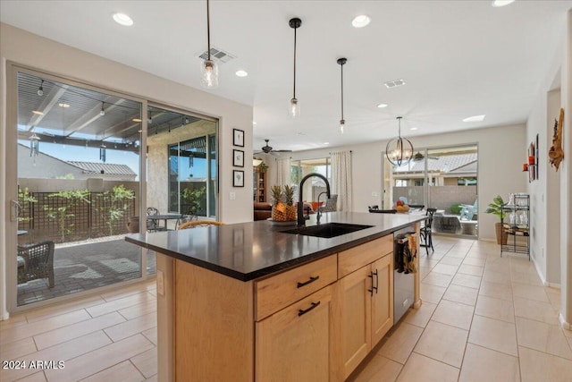 kitchen featuring a center island with sink, decorative light fixtures, light brown cabinetry, sink, and dishwasher