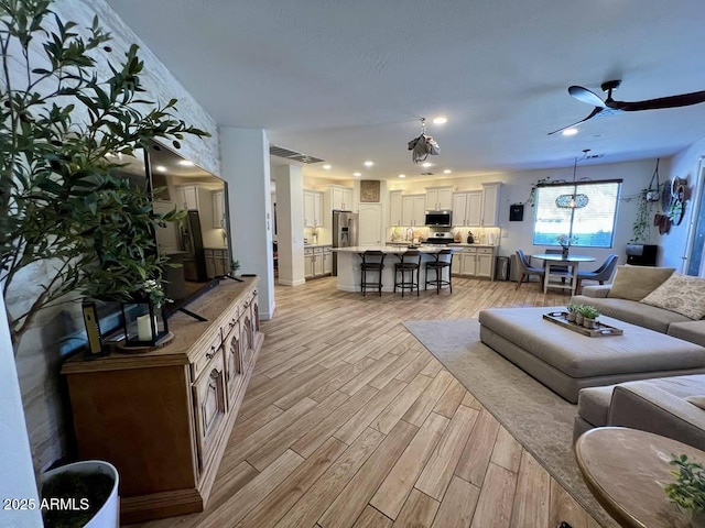 living room featuring ceiling fan and light wood-type flooring