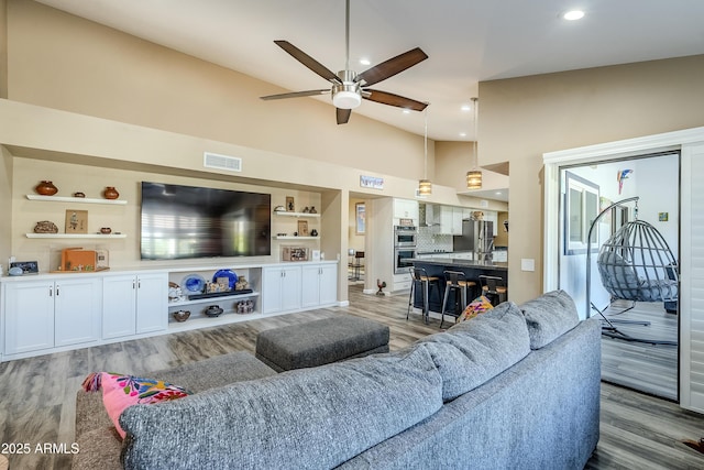 living room with light hardwood / wood-style flooring, vaulted ceiling, and ceiling fan