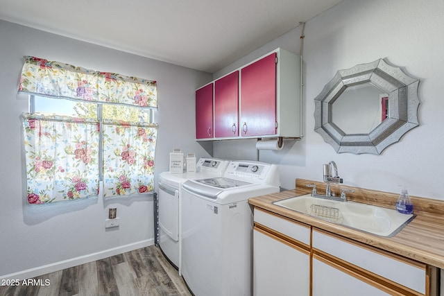 washroom with sink, washing machine and clothes dryer, hardwood / wood-style floors, and cabinets