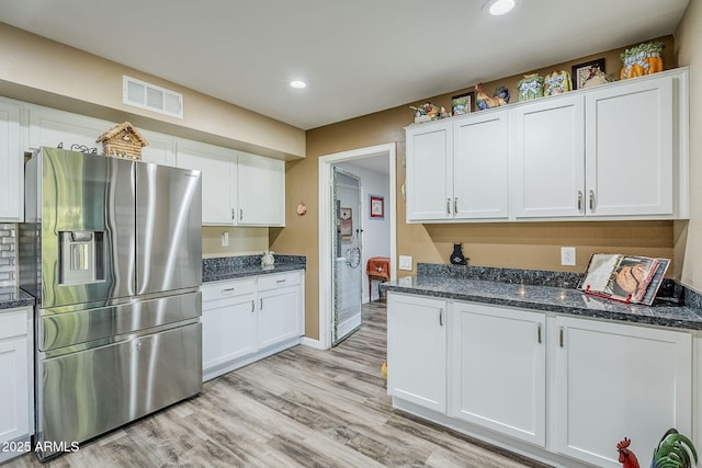 kitchen with white cabinets, light wood-type flooring, and stainless steel fridge