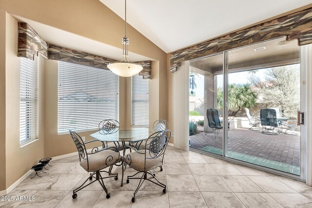 dining room featuring baseboards, vaulted ceiling, and a wealth of natural light