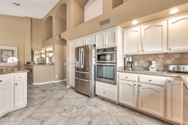 kitchen with visible vents, stainless steel appliances, white cabinetry, and decorative backsplash