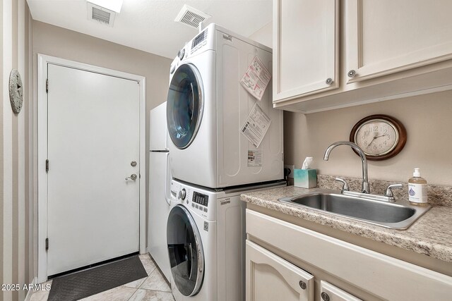 washroom with visible vents, stacked washing maching and dryer, a sink, and cabinet space