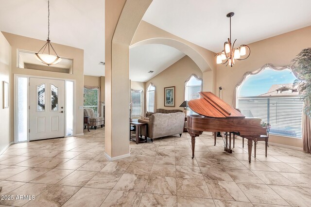 foyer entrance featuring baseboards, arched walkways, and a notable chandelier