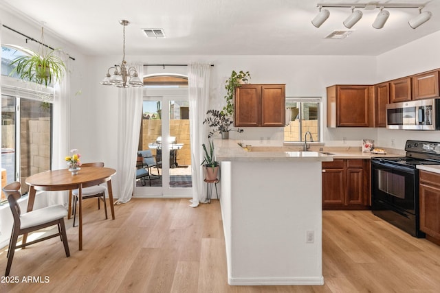2150 E Bell Rd Unit 1088, Phoenix, AZ 85022 - kitchen with stainless steel microwave, black electric range, light countertops, light wood-style floors, and a chandelier