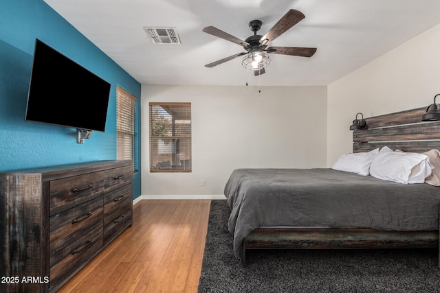 bedroom featuring a ceiling fan, baseboards, visible vents, and wood finished floors