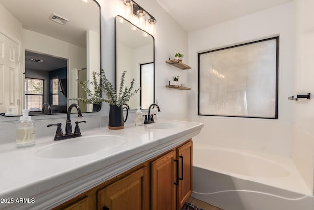 full bathroom featuring visible vents, a sink, a bath, and double vanity