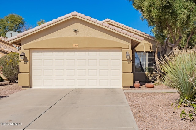 view of front of property with a garage, concrete driveway, a tile roof, and stucco siding