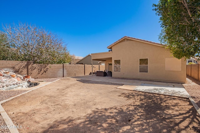 rear view of house with a tile roof, a fenced backyard, a patio, and stucco siding