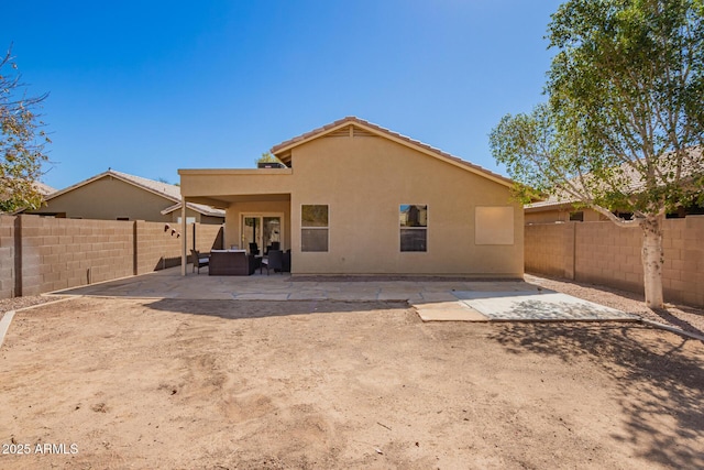 rear view of house with stucco siding, a fenced backyard, and a patio