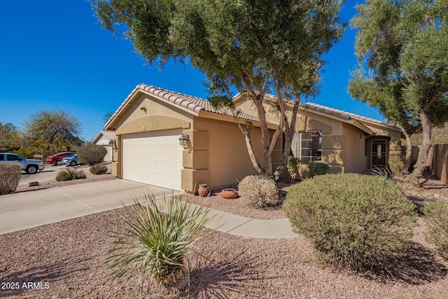 view of front facade with concrete driveway, a tile roof, an attached garage, and stucco siding