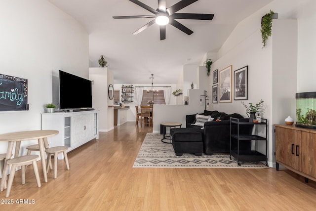 living area with lofted ceiling, light wood-style flooring, and ceiling fan with notable chandelier