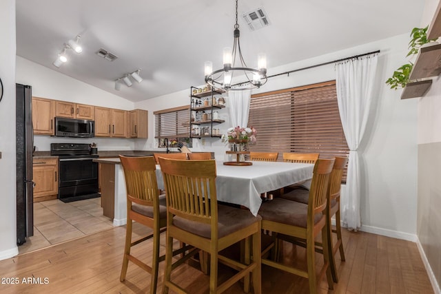 dining space with lofted ceiling, visible vents, light wood finished floors, and an inviting chandelier