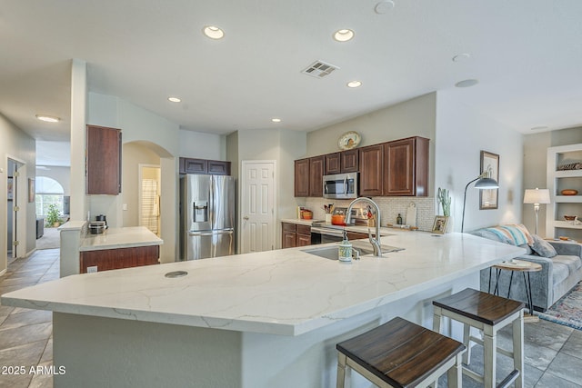 15848 W Calavar Rd, Surprise, AZ 85379 - kitchen with appliances with stainless steel finishes, a sink, a peninsula, recessed lighting, and arched walkways